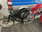 Wem gehört dieses Fahrrad? Es handelt sich um ein schwarzes Fahrrad der Marke Bocas mit einem weißen Lenkerkorb und einem grau-roten Kindersitz.
