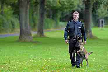 Dieses Bild zeigt einenHundeführer der Polizei Bremen mit seinem Diensthund im Park