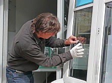 Ein Kriminalbeamter sichert Spuren auf einem aufgebrochenen Fenster.
