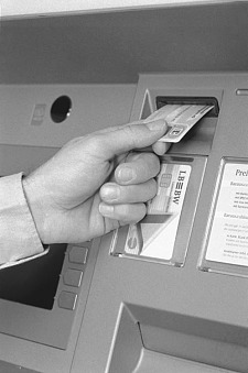 Eine Debitkarte wird von einer Person in einen Geldautomaten eingeführt