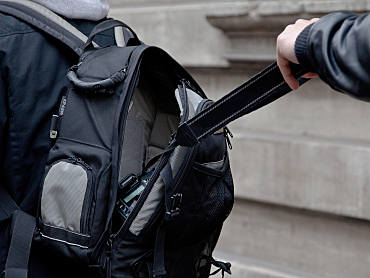 Person greift in einen Rucksack nach einem Laptop 