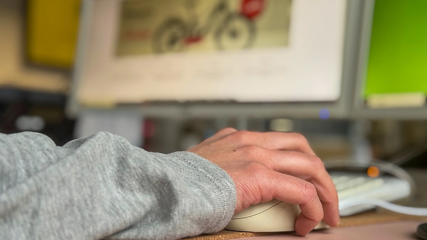 Person sitzt an einem PC und schaut sich eine mutmaßliche Fakeshop-Seite an