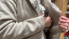 Person lässt eine Weinflasche in Jackeninnentasche verschwinden