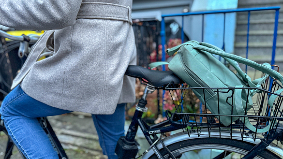 Person auf einem Fahrrad samt Fahrradkorb mit Rucksack 