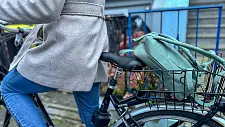 Person auf einem Fahrrad samt Fahrradkorb mit Rucksack 