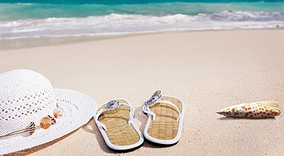 Badelatschen, Sonnenhut im Sand am Meer