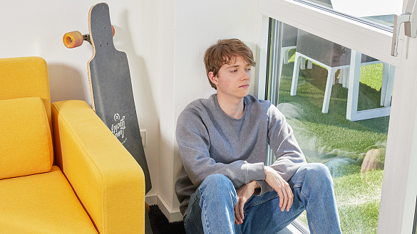 Nachdenklicher Junge sitzt an einem Fenster