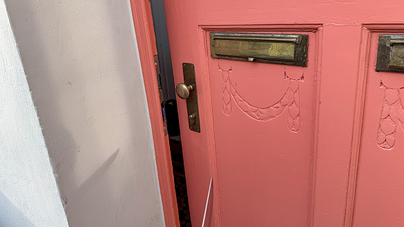 An der Wand einer geöffneten Tür erkennt man den Schatten eines Messers 