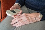 Ältere Person hält ein schnurloses Telefon in der Hand