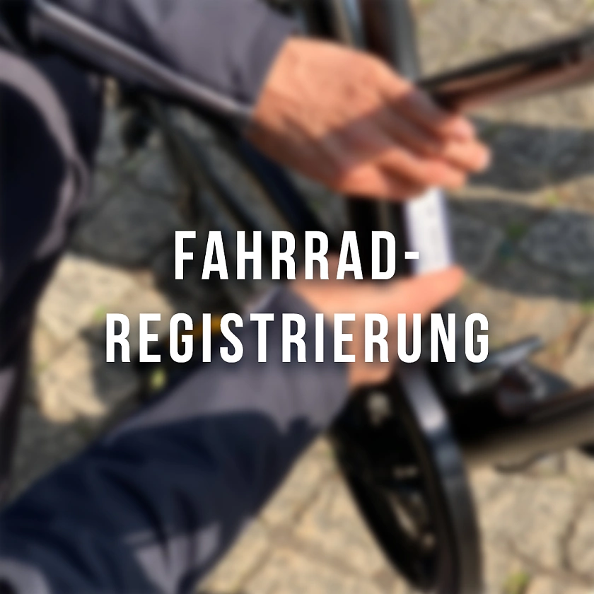Auf dem Bild ist zu sehen, wie ein Polizist den Aufkleber zur Fahrradregistrierung auf ein Fahrrad klebt.