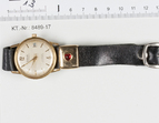 Asservat 1.3: Armbanduhr der Marke Roberta, schwarzes Lederarmband, rotes Herz auf einer Metallschnalle