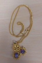 Kette in gold mit lila Steinen.