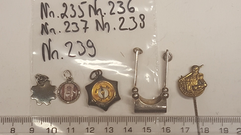 Asservate 235 bis 239: Diverse Kettenanh&auml;nger und eine Anstecknadel mit Person in R&uuml;stung und einem Schwert / Aufschrift: SACRO