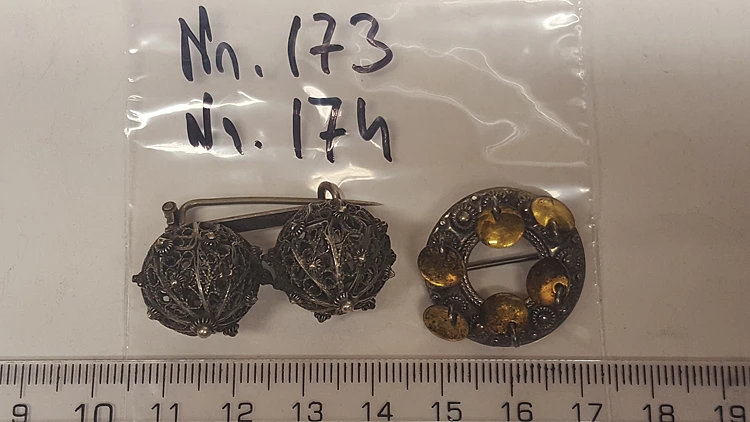 Asservate 173 bis 174: zwei bronzefarbene Broschen / ein mit goldenen Metallpl&auml;ttchen besetzt