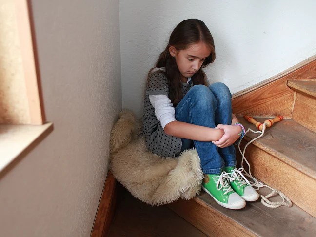 Trauriges Mädchen in der Ecke einer Treppe