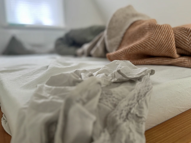 Unterhose auf dem Bettrand eines unordentlichen Bettes 