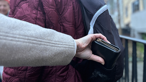 Hand, die ein Portemonnaie in einem Rucksack ergreift